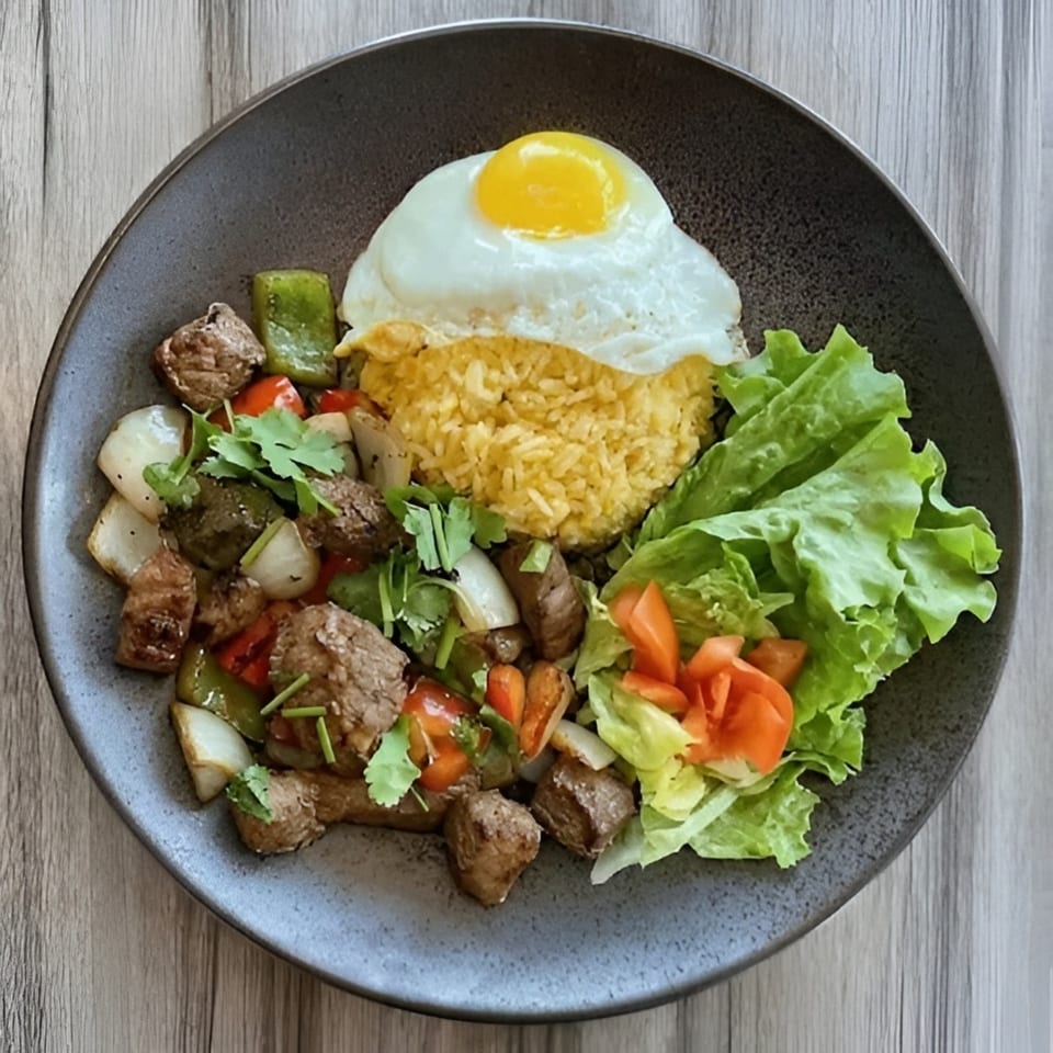 Plate of grilled meat, rice, fried egg, roasted vegetables, fresh lettuce, tomatoes, and herbs on a dark ceramic dish.